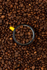 Brown roasted coffee beans with yellow cup in the middle.