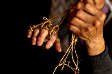 Hands of old woman with polyarthritis disease. Canvas strings on fingers of elderly lady, puppets....