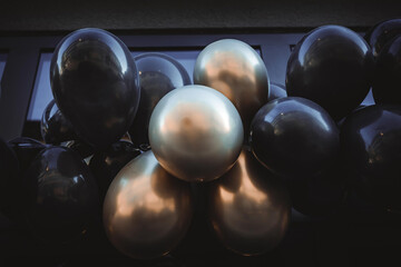 black and golden balloons in front of a window