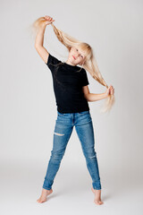 Ganzkörperporträt eines blonden Mädchens in einem schwarzen T-Shirt und Blue Jeans