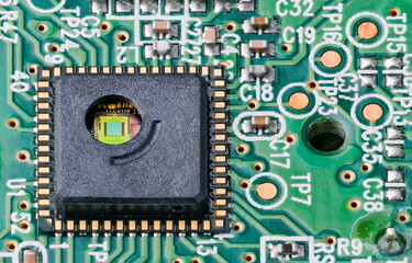 Green silicon die and gold wires inside round hole of integrated circuit. Close-up of...