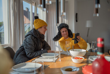 A couple is sitting at the dining table in winter clothes at home, it is cold, they are freezing, save energy.