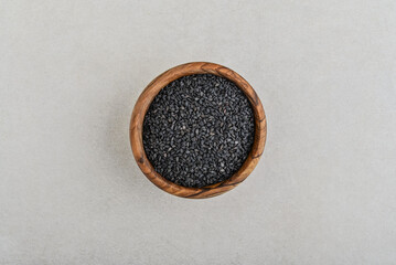Raw organic black sesame seeds in wooden bowl on concrete background