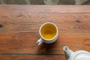 green herbal tea in a white cup with a saucer on a wooden table in a green autumn garden on a sunny day
