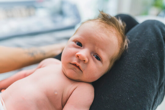 Caucasian infant boy with cute brown hair laying on his mother lap, looking at the camera. Face close up. High quality photo
