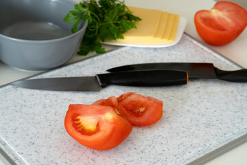 kitchen board with knives and red tomato