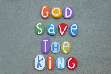 God Save the King, creative slogan composed with multi colored stone letters over green sand