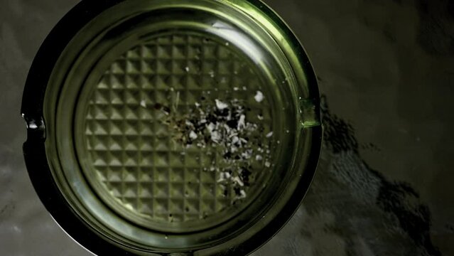 Hand picks up cigarette to smoke and puts it back on ashtray. High quality 4k footage