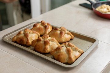 Tray with pan de muerto, freshly baked, on the counter of a Mexican kitchen
