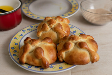 Pan de muerto freshly baked at home, on a plate on the counter of a Mexican kitchen