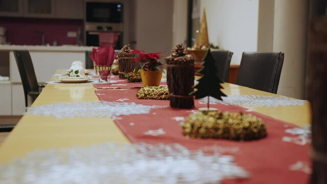Table served for Christmas dinner. Christmas Decorated Table at Home with Candles, Different Dishes. Christmas Tree and Fireplace on background. Celebrating interior for New Year Party at Home