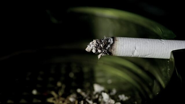 Lit cigarette burning in ashtray close up.