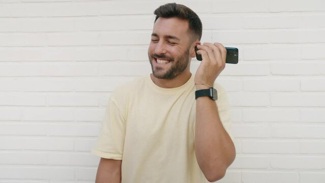 Young hispanic man smiling confident listening audio message by the smartphone over isolated white background