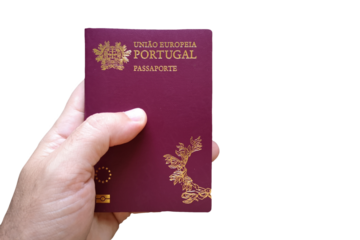 Man's hand holding Portuguese passport with defocused Portuguese flag in the background. Written in Portuguese: European Union Portugal. Passport.