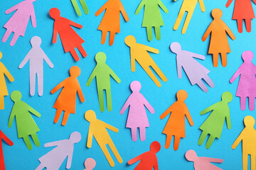 Many different paper human figures on light blue background, flat lay. Diversity and inclusion...