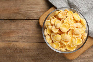 Bowl of tasty corn flakes on wooden table, top view. Space for text