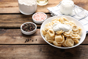 Tasty dumplings in bowl on wooden table, space for text