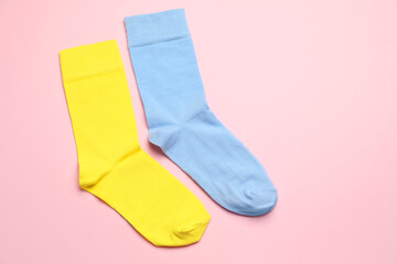 Colorful socks on light pink background, flat lay. Space for text
