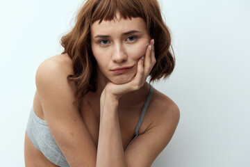 Fototapeta premium a pleasant, beautiful, tanned woman stands with a thoughtful, relaxed look and leaning on her hand looks at the camera
