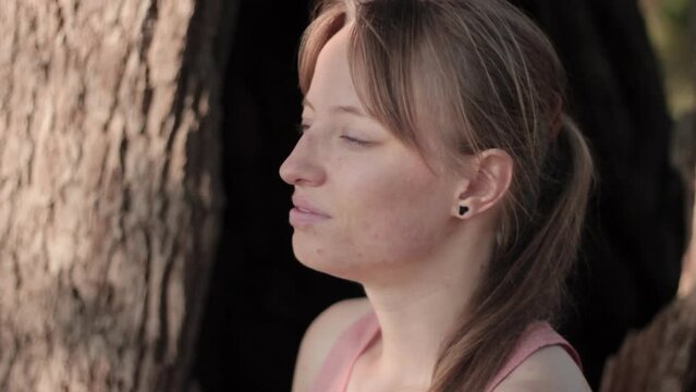 Close up shot of a young woman sitting beneath the tree and deep breathe for relaxing