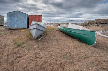 Canoes, sheds, and sled, on the edge of the Arctic Ocean at Iqaluit, Nunavut