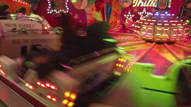 A fair at dusk with people riding swinging rides and enjoy