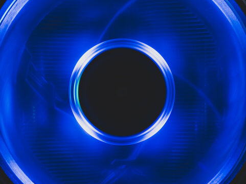 Computer cooling fan with blue light abstract background. cooler in action with led close up. power in motion concept
