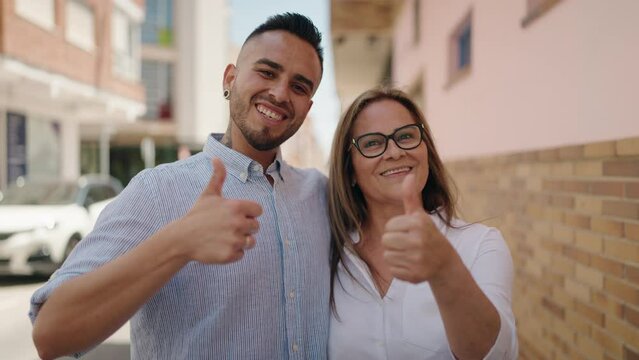 Man and woman mother and daugther doing ok gesture with thumbs up at street