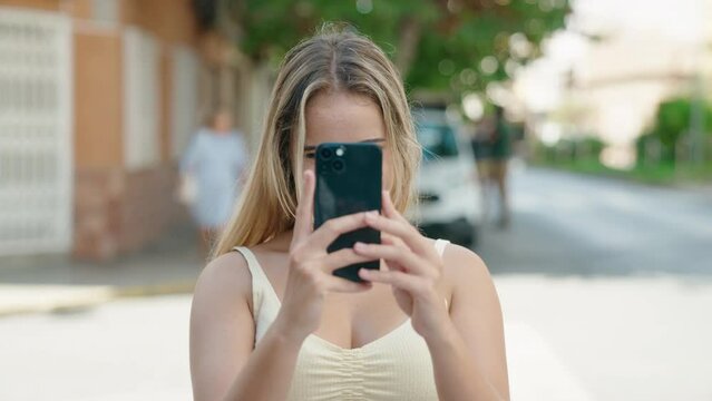 Young blonde woman smiling confident make photo by smartphone at street