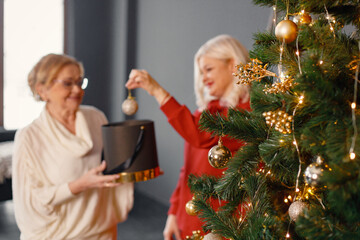 Old woman with her adult daughter decorating Christmas tree