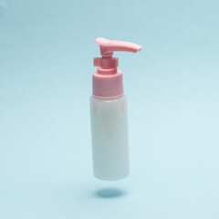 Bottle cream or liquid soap with dispenser levitating on a blue background