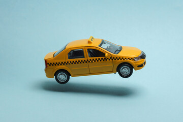 Miniature taxi car levitating on a blue background with a shadow