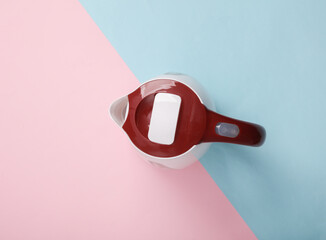 Plastic electric kettle on a blue-pink pastel background. Top view