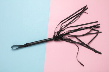 Leather whip on a blue-pink pastel background. Sex games domination