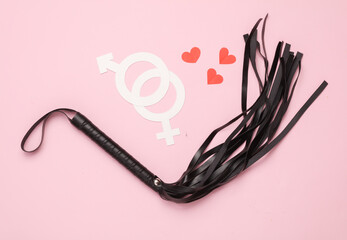 Leather whip from a sex shop, gender symbols with hearts on a pink background. Sex, love games
