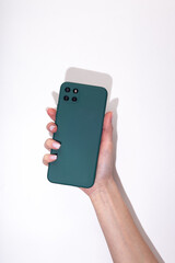 Woman's hand holds a smartphone in a green protective cover on a white background