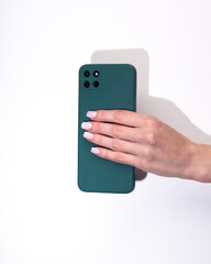 Woman's hand holds a smartphone in a green protective cover on a white background
