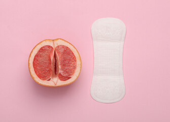 Gynecology, female intimate hygiene, menstruation. Half of grapefruit symbolizing female vagina with pads on pink background. Top view