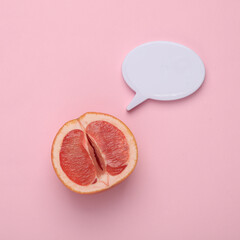 Gynecology, female intimate hygiene. Half of ripe grapefruit symbolizing the female vagina and empty speech bubble on a pink background. Top view