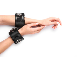 Female hands in leather handcuffs from sex shop on white background. Domination, sex games