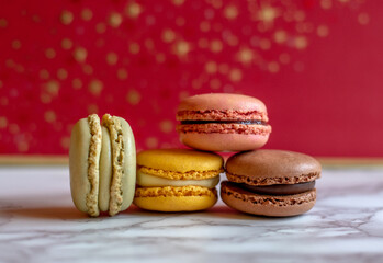 holiday macaron still life, with colorful french macarons against a red and gold back ground