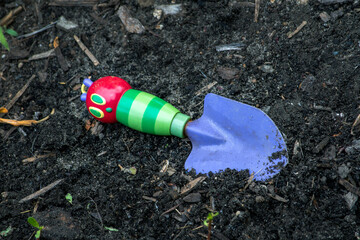 Child's toy shovel in the garden dirt
