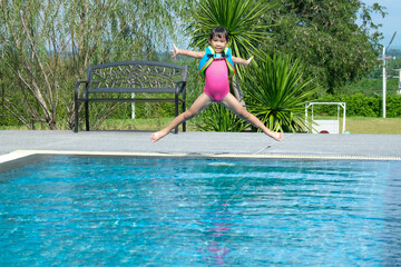 Naklejka premium Little girl plays in the outdoor swimming pool of tropical resort during family summer vacation. Kids learning to swim. Healthy Summer Activities for Kids.