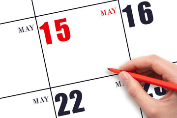 A hand holding a red pen and pointing on the calendar date May 15. Red calendar date, copy space,...