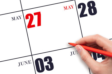 A hand holding a red pen and pointing on the calendar date May 27. Red calendar date, copy space,...