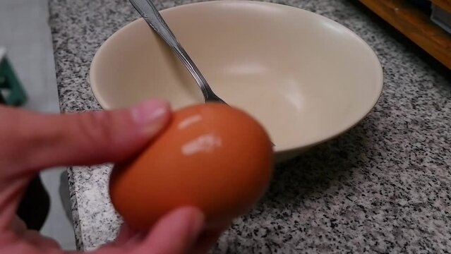 The chef's hand is cracking an egg in a slow motion bowl.