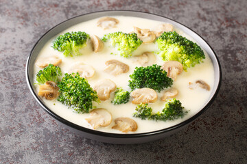 Thick fragrant cream soup with broccoli and champignon mushrooms close-up in a bowl on the table....