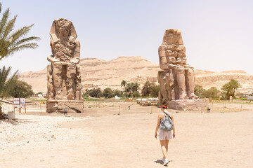 Woman walking towards an ancient egyptian statues