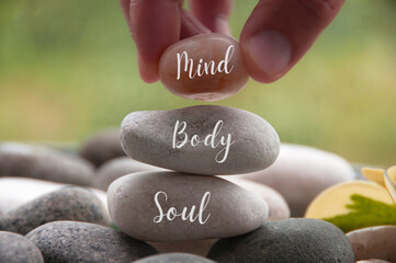 Hand holding zen stone with words Mind, Body, Soul. Spa concept