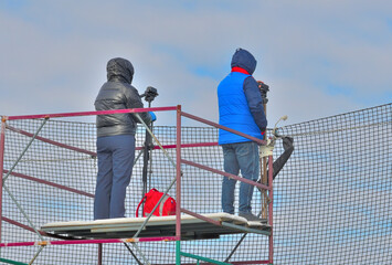 Photojournalists watch the match outdoors on an autumn day